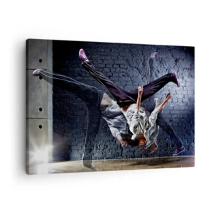 Canvastavla - Bild på duk - En dansare i ett dynamiskt hopp mot en tegelvägg - 70x50cm - Gatans stjärna - Modern väggdekoration för vardagsrum och sovrum ARTTOR