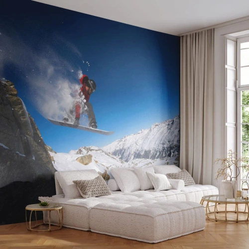 Fototapet Standard Eco - En snowboardåkare hoppar mot en bakgrund av snötäckta berg. - 100x70cm - Så blev du en del av vyn - Modern väggdekoration för vardagsrum och sovrum ARTTOR