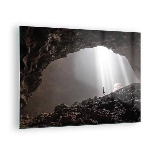Glastavla - Bild på glas - En figur i en grotta upplyst av ljusstrålar, omgiven av mörka stenar - 70x50cm - Ljusfylld grotta - Modern väggdekoration för vardagsrum och sovrum ARTTOR