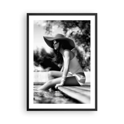 Affisch i svart ram - Ett svartvitt fotografi av en kvinna i hatt som sitter vid vattnet. - 50x70cm - En sommardröm - Modern väggdekoration för vardagsrum och sovrum ARTTOR