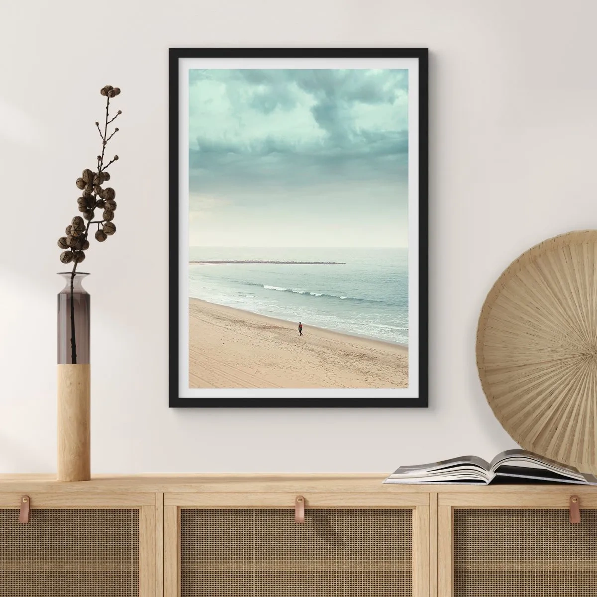 Affisch i svart ram - En ensam gestalt vandrar längs havsstranden under en mulen himmel. - 50x70cm - På jakt efter frid - Modern väggdekoration för vardagsrum och sovrum ARTTOR