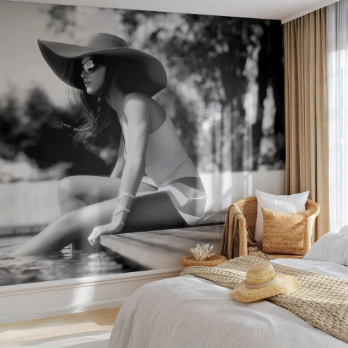 Fototapet Standard Eco - En kvinna med hatt som sitter vid poolen - 100x70cm - En sommardröm - Modern väggdekoration för vardagsrum och sovrum ARTTOR