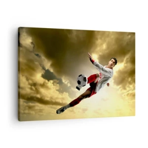 Canvastavla - Bild på duk - En fotbollsspelare i ett dynamiskt hopp som sparkar bollen mot himlen - 70x50cm - Fotbollshimmel - Modern väggdekoration för vardagsrum och sovrum ARTTOR